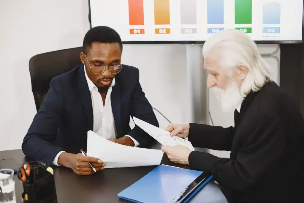 Canal+ débloque des millions pour le cinéma : la controverse de Cannes persiste Réunion d'affaires autour d'une table avec documents financiers et graphiques de budget