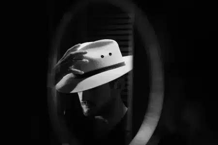 Personne ajustant un chapeau d'été devant un miroir en lumière naturelle