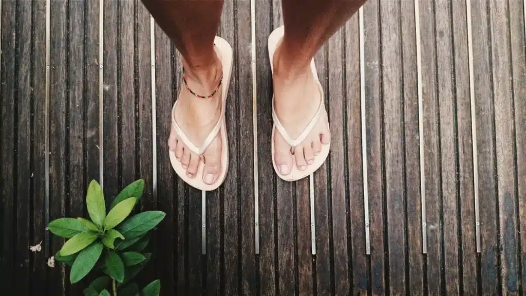 Tongs minimalistes posées sur du pavé urbain aux côtés d'une veste et d'un pantalon structurés, lumière estivale