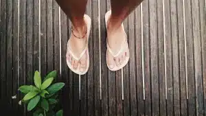 Tongs minimalistes posées sur du pavé urbain aux côtés d'une veste et d'un pantalon structurés, lumière estivale