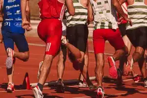 Stade d'athlétisme en soirée avec athlètes en action et équipements de compétition
