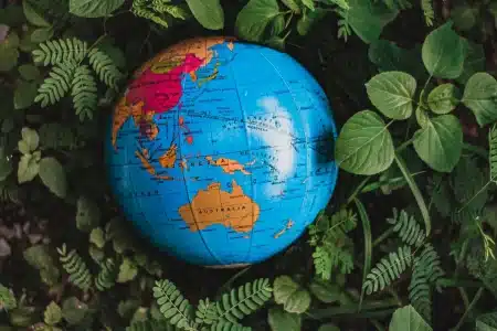 Mains tenant un globe terrestre avec des documents environnementaux en arrière-plan