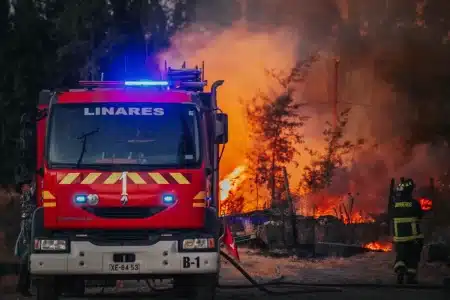 Pompiers et secouristes face aux flammes dans une forêt dévastée, avec des personnes sinistrées recevant de l'aide en ar