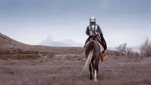 Campement militaire médiéval dévasté avec soldats et chevaux dans la brume