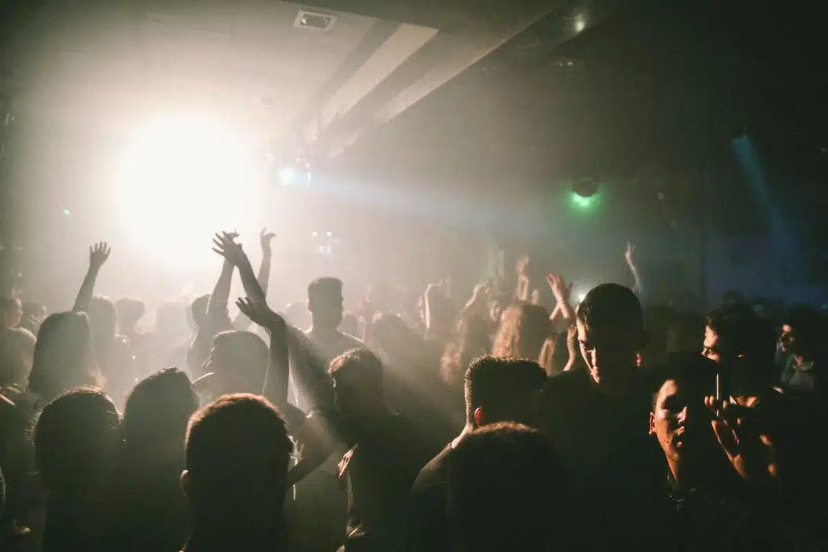 Foule dansante dans une discothèque illuminée par des lumières néon et des projecteurs colorés