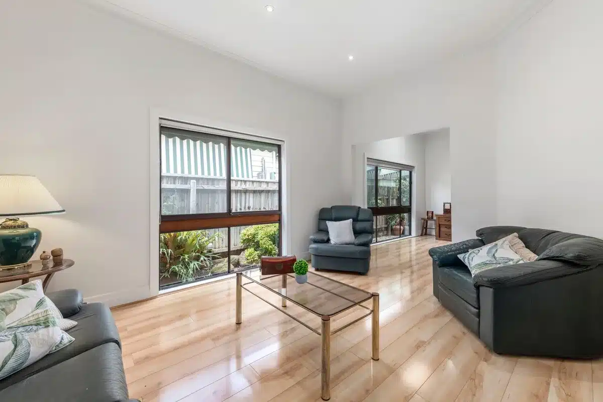 Salon aménagé avec mobilier repositionné et luminosité optimisée pour mise en avant immobilière