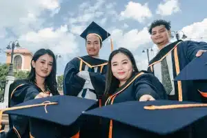 Mains anonymes tendues vers des livres et un mortier de graduation symbolisant l'accès à l'éducation