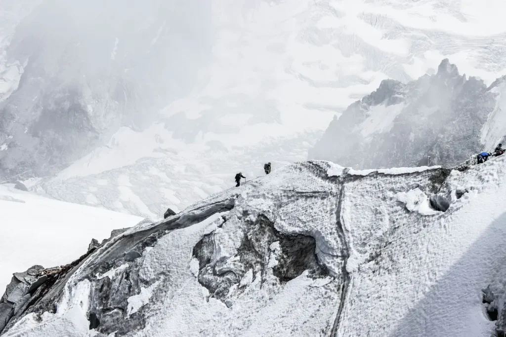 Randonneurs explorant un paysage alpin avec glaciers et sommets enneigés.