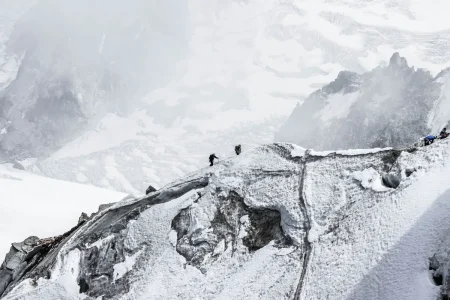 Randonneurs explorant un paysage alpin avec glaciers et sommets enneigés.