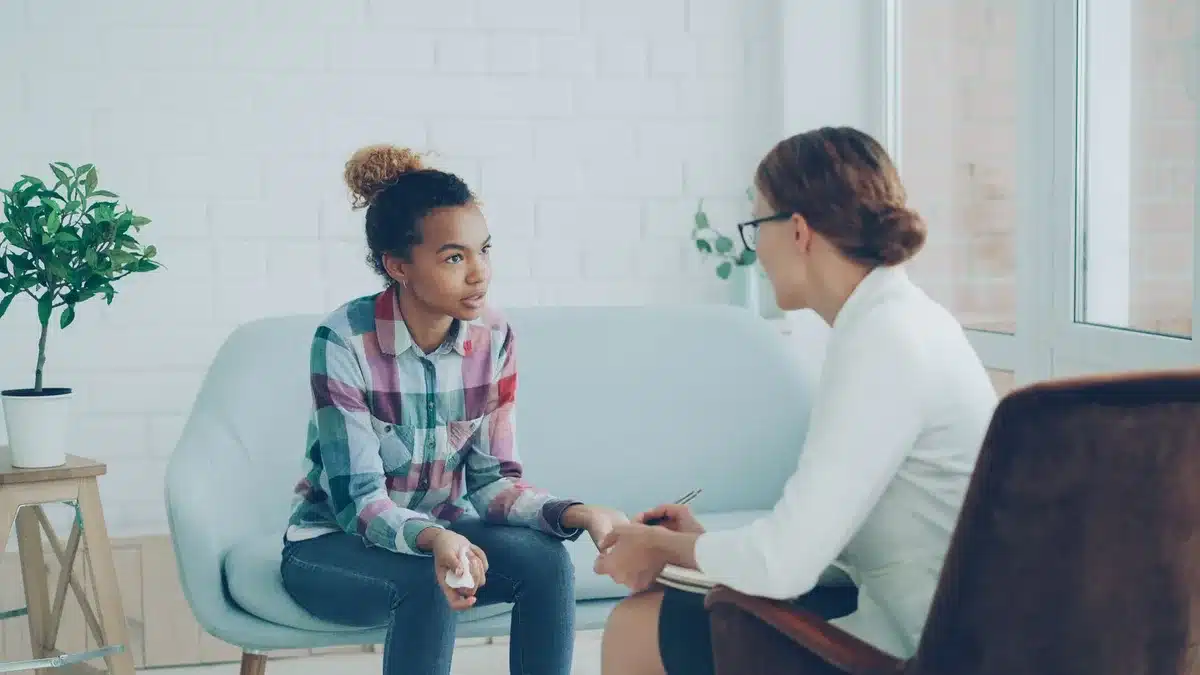 Professionnel écoutant attentivement un jeune lors d'une séance de soutien psychologique