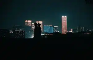 Silhouette d'un héros suspendu entre les gratte-ciel d'une ville la nuit, illuminée par les lumières urbaines