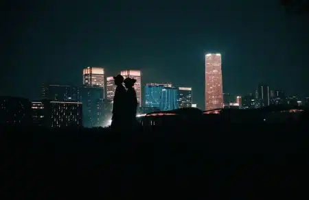 Silhouette d'un héros suspendu entre les gratte-ciel d'une ville la nuit, illuminée par les lumières urbaines