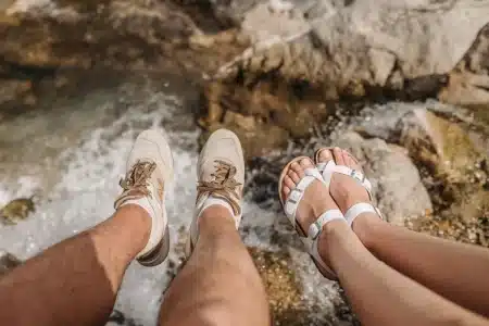 Pieds portant des sandales compensées marchant sur un trottoir ensoleillé en été