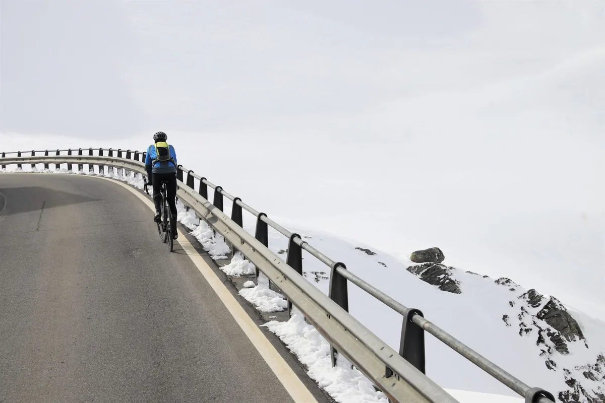 Cycliste en attaque solitaire sur une route de montagne, détachée du peloton.