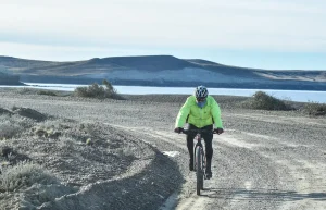 Cycliste solitaire en maillot coloré franchissant une montée, le peloton loin derrière