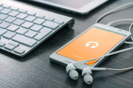 Main numérique touchant une onde sonore numérique brillante sur écran sombre, symbolisant l'IA musicale