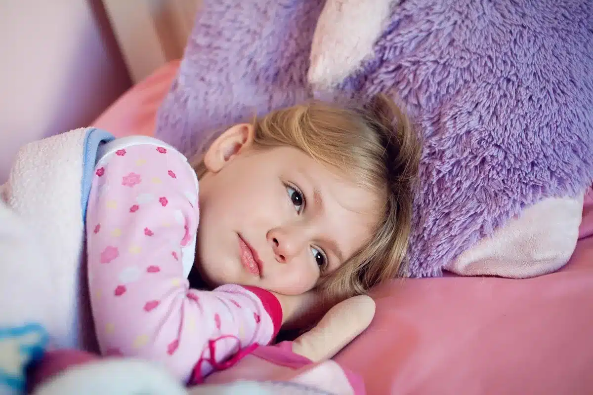 Chambre d'enfant avec zones distinctes : coin sommeil, espace jeu et bureau près de la fenêtre