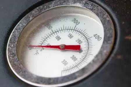Thermomètre affichant une température extrêmement élevée sous un soleil intense, avec chaleur visible