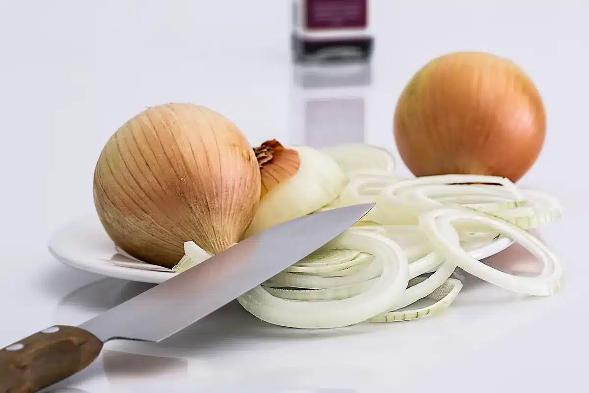 Mains d'un jeune coupant des légumes frais dans une cuisine d'atelier.