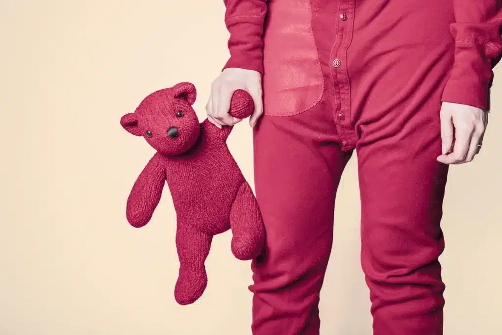 Un ours en peluche et un sac d'enfant sur un banc d'école, aire de jeux en arrière-plan