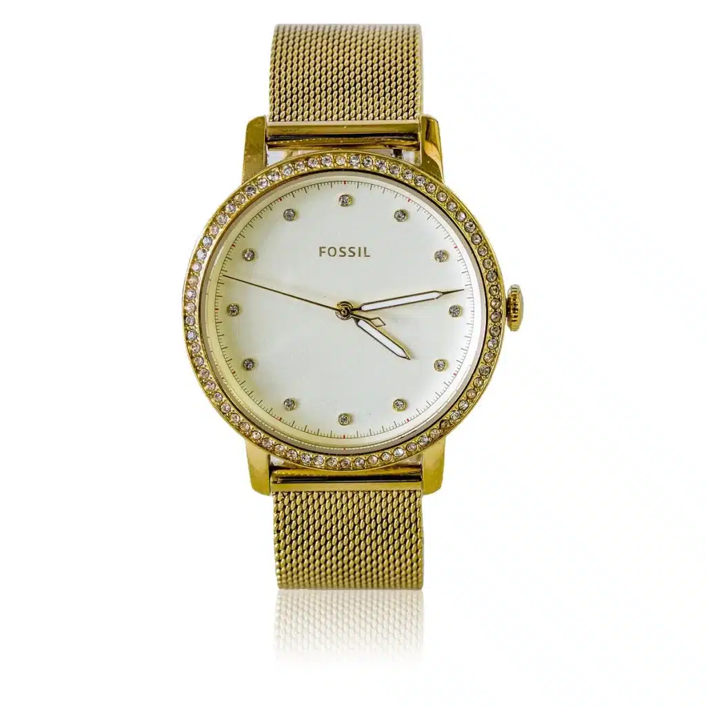 Poignet anonyme portant une montre ovale près d'une robe en satin et d'une minaudière