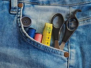 Mains mesurant une fenêtre avec un mètre ruban, tissus de rideaux à proximité