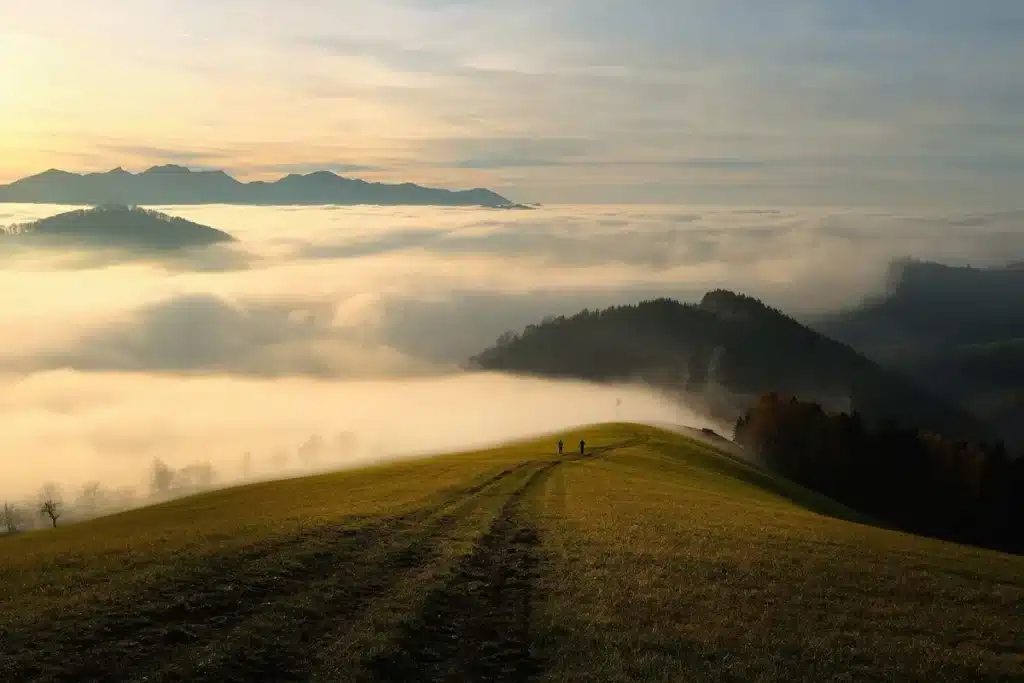Sac à dos et bâtons posés près d'un cairn sur un sentier de montagne au crépuscule