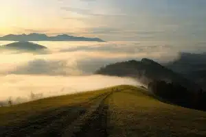 Sac à dos et bâtons posés près d'un cairn sur un sentier de montagne au crépuscule