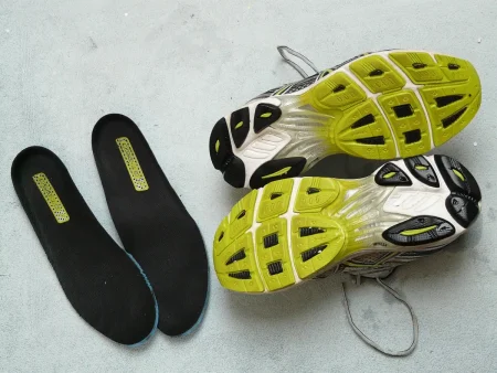 Couloir d'un stade en plein jour avec des pointes d'athlétisme posées et un programme plié