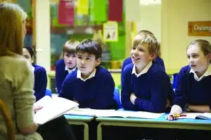 Atelier périscolaire clair avec enfants anonymes manipulant matériaux créatifs