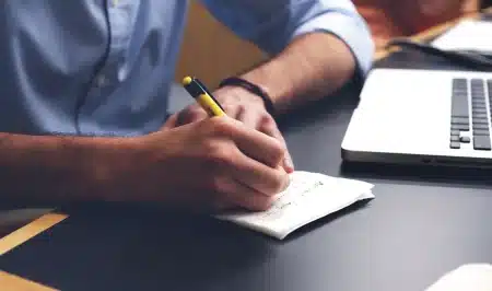 Bureau en journée avec rapports, ordinateur et mains consultant des graphiques