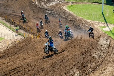 Corner d'une piste de BMX en pleine journée avec coureurs anonymes et mains sur guidon