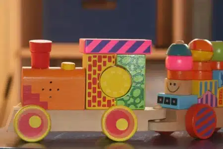 Salle de jeu d'hôpital en journée avec tiroirs de kits sensoriels et jouets apaisants