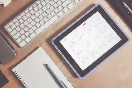 Mains anonymes feuilletant des documents sur un bureau éclairé par la lumière du jour