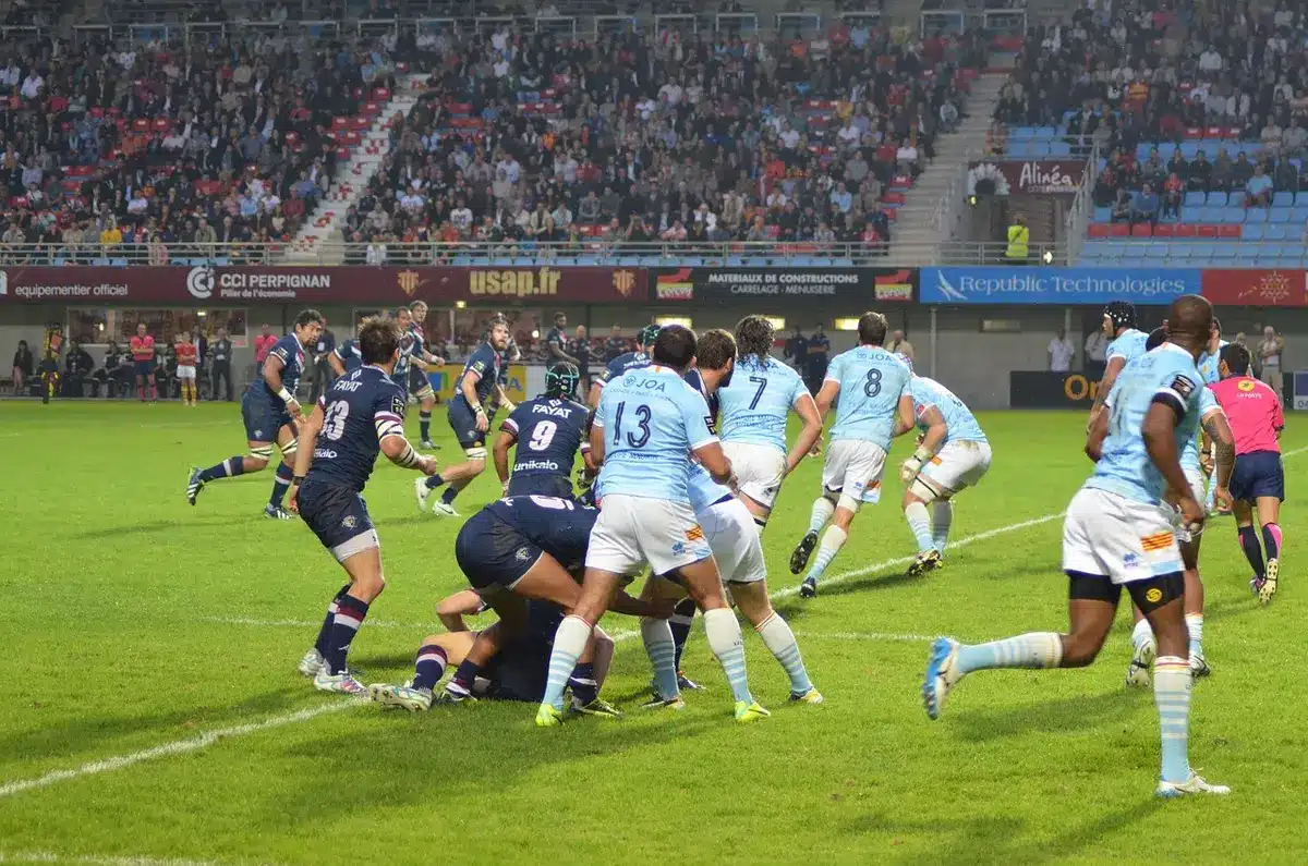 Action collective en fin de match de rugby montrant une percée et affrontement en plein jour