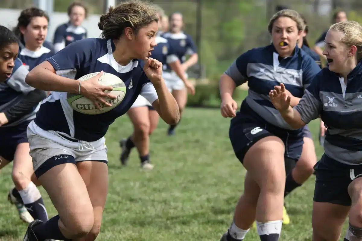Groupe de joueuses de rugby essoufflées réorganisant la défense sous le soleil