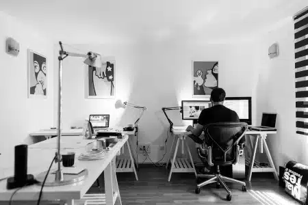 Bureau à domicile en plein jour avec ordinateur, bloc-notes et une main tenant une feuille