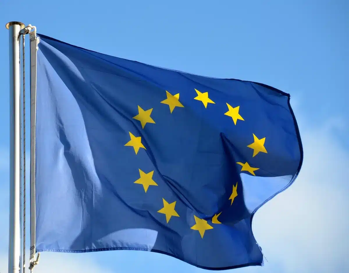 Chaîne d'assemblage avec pièces automobiles et drapeau européen en arrière‑plan flou