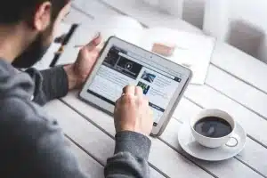 Espace de travail lumineux avec ordinateur portable, pages imprimées et mains en train d'écrire