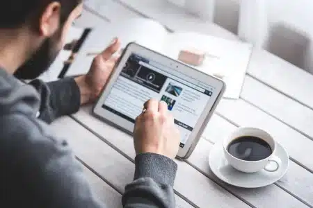 Espace de travail lumineux avec ordinateur portable, pages imprimées et mains en train d'écrire