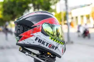 Mains gantées déposant un casque de moto sur une table de paddock en plein jour, documents et radiographie visibles