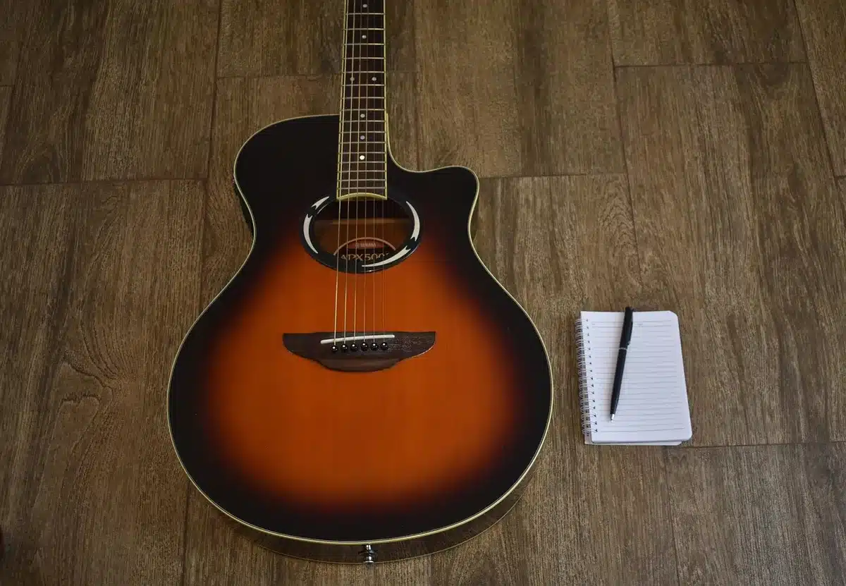 Auteur-compositrice en studio avec guitare et ordinateur, lumière naturelle