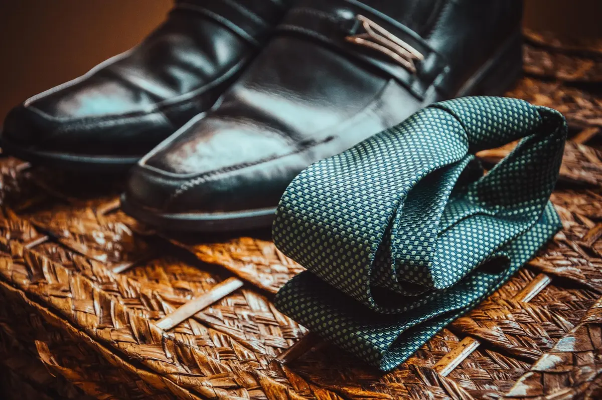 Jean à la coupe nette avec veste bien taillée et baskets en cuir posés près d'un fauteuil