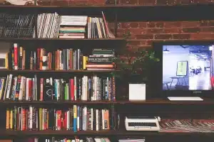 Mains feuilletant un roman sur une table de bibliothèque en plein jour, roses à côté