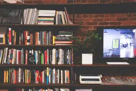 Mains feuilletant un roman sur une table de bibliothèque en plein jour, roses à côté
