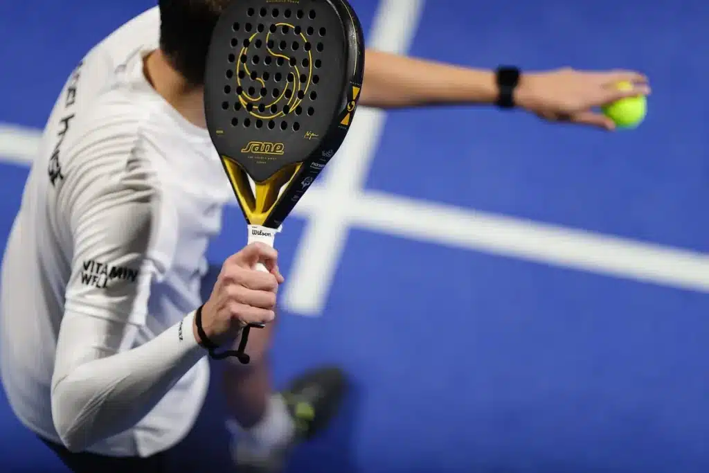 Court de tennis en plein jour avec raquettes sur un banc et trophées en arrière‑plan