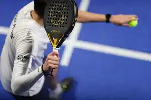 Court de tennis en plein jour avec raquettes sur un banc et trophées en arrière‑plan