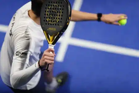 Court de tennis en plein jour avec raquettes sur un banc et trophées en arrière‑plan