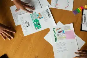 Salle de classe en plein jour, mains anonymes posant des dossiers sur une table
